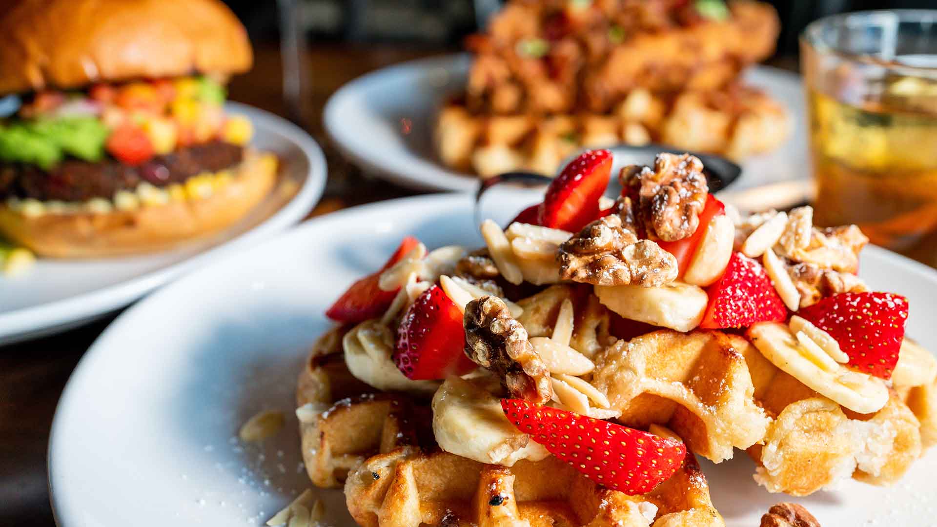 Delicious Fruit and Nut Waffles with Pearl Sugar, Strawberries, Bananas, Almonds, Walnuts, Powdered Sugar, Butter, and Maple Syrup - served fresh at Artisan's Table during brunch.